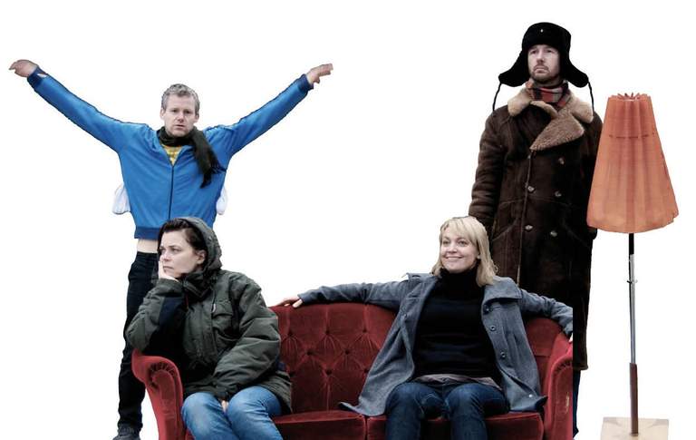 Two persons sitting on a sofa and two persons standing behind it.