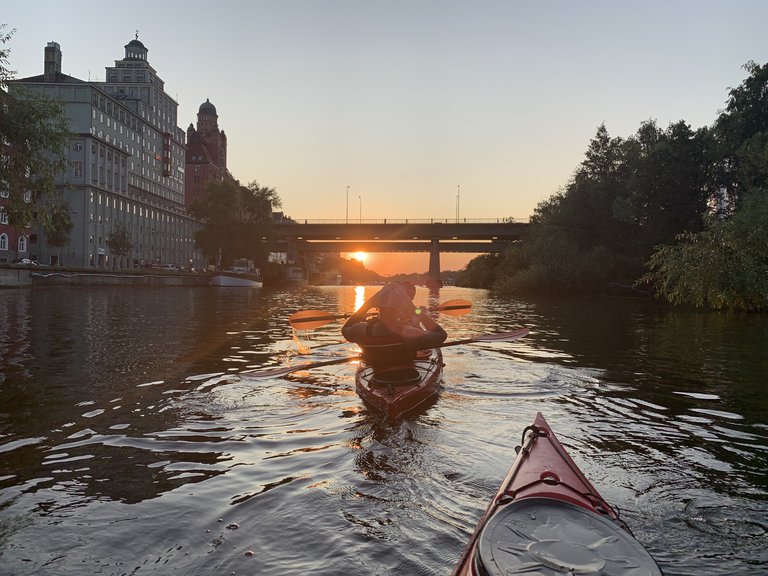 A person in a kayak looking at a sunset.