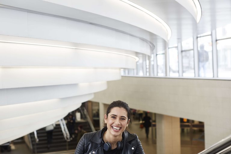 A smiling woman with headphones around her neck on her way out of a metro station in Stockholm.