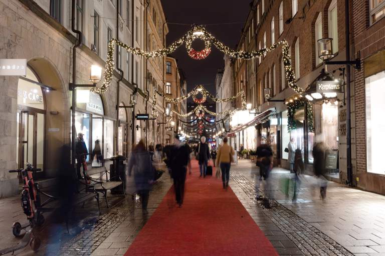 People walking in a pedestrian shopping street, decorated with Christmas lighting