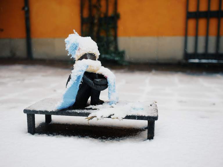 Public art in Stockholm. Snow has fallen on the small iron boy statue in Gamla Stan.