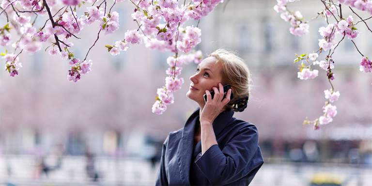 Woman talking on the phone under the cherry blossom in Stockholm.