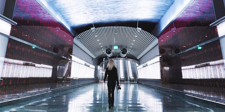 T-Centralen subway station in Stockholm. The new Citybanan-annex. A young woman holding a camera is walking along a brightly lit tunnel.