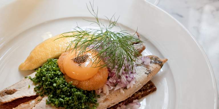 Classic Swedish food. Fried herring on rye bread, topped with chives, an egg yolk, red onion, dill and roe. There are several good restaurants in Stockholm where you’ll be treated to classic Swedish cuisine.