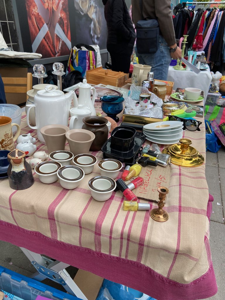 Plates, cups, jugs, candle holders, cosmetics and other objects on a table.