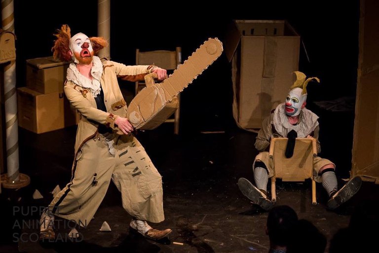 Clown with a saw and clown sitting on a chair.