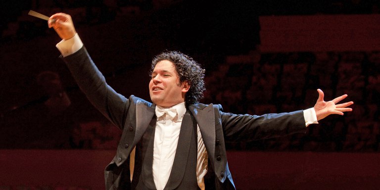 A conductor, mid-concert, directs his orchestra from his stand.