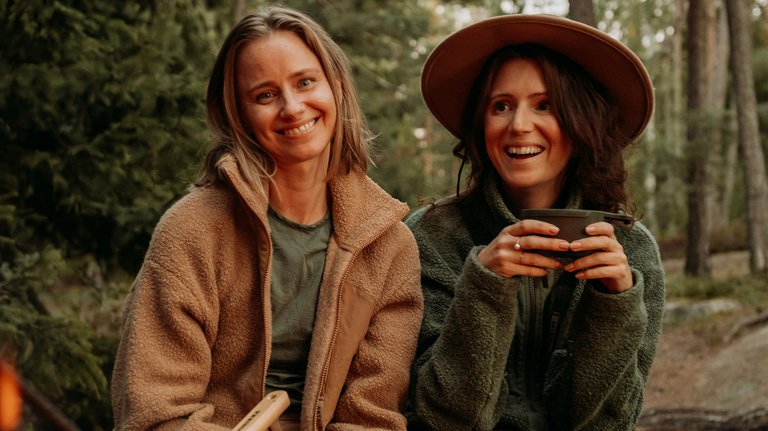 Two women smiling in front of an open fire