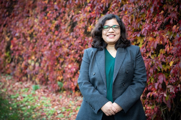 Bhanupriya Chouhan smiling in front of autumn foliage.