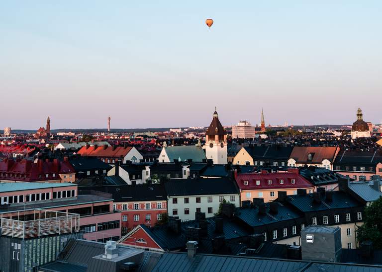 A beautiful view of Stockholm rooftops with a hot-air balloon floating in the sky
