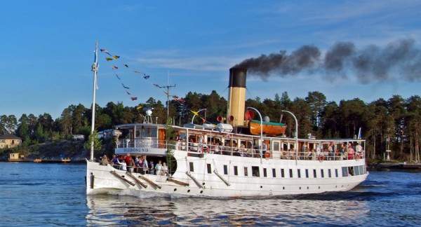 A steam boat with many people onboard.