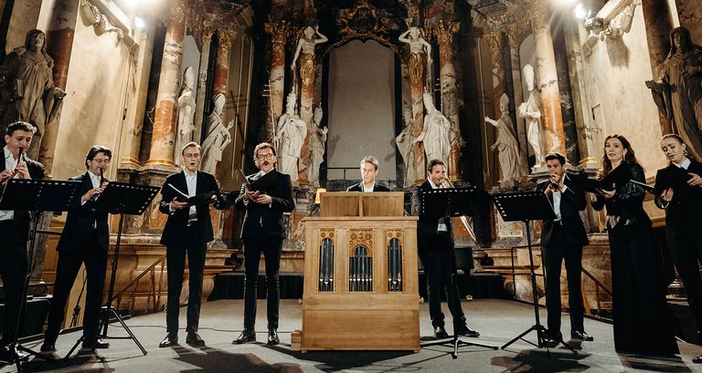 Orchestra playing in a venue decorated with sculptures.