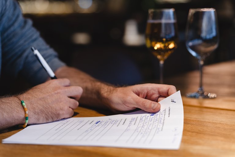 A person writing answers on a sheet of paper during a pub quiz,