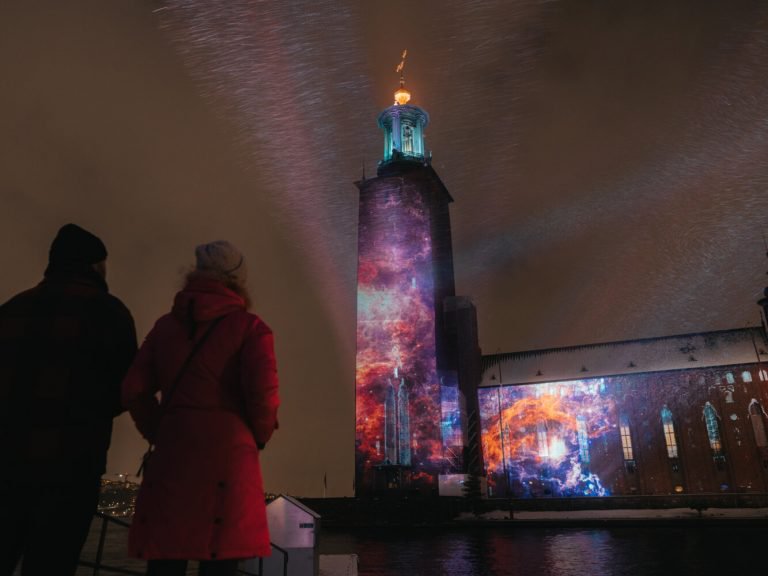 Stockholms stadshus med ljusinstallation på väggarna.