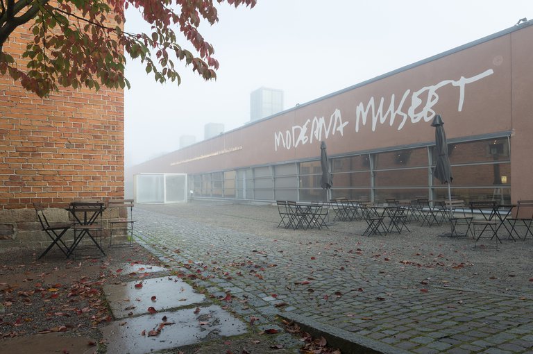 Museer i Stockholm. Moderna Muset på Skeppsholmen, exteriör. Höst. En tätdimma ligger nära marken utanför huvudentrén till museet.