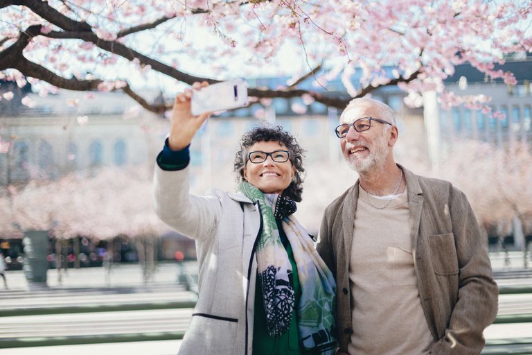 Two people stop to take a photo under the cherry blossoms at Kungsträdgården, Stockholm