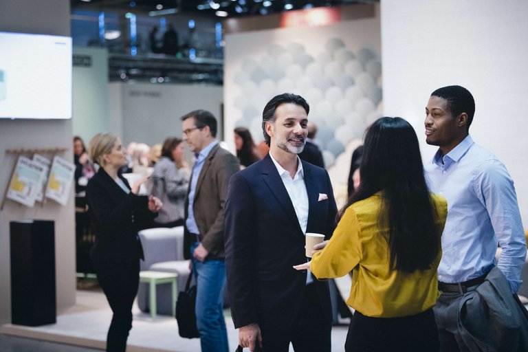 Groups of people stand around talking at a networking event in Stockholm.