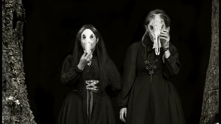 Black-and-white photo of the artists holding animal skullsin front of their faces