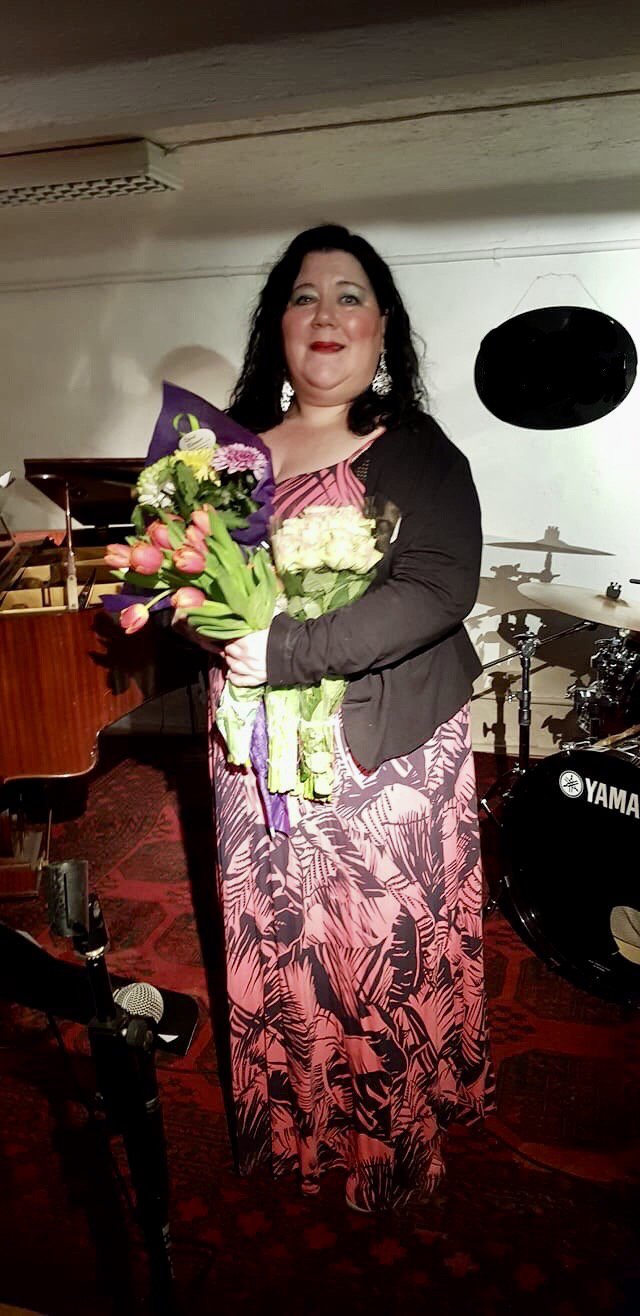 A woman in a long dress with flowers in her hands.