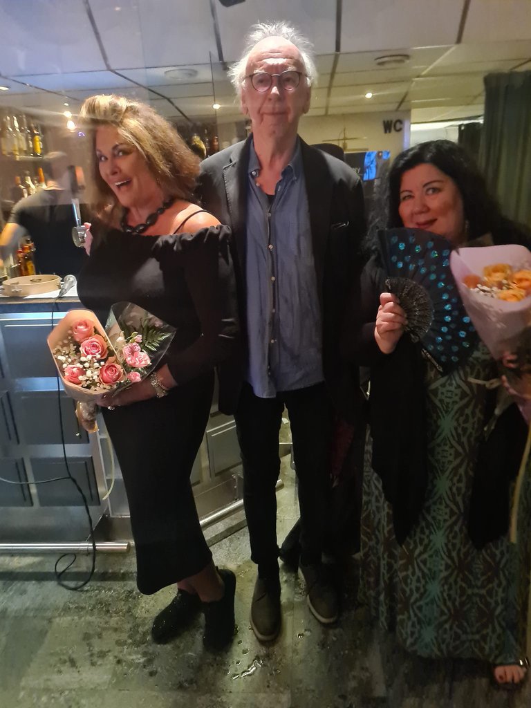 Two women with flowers and one man.