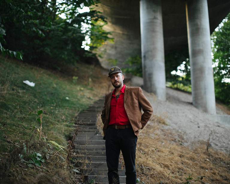 The singer-songwriter Johan Airijoki standing outdoors at the stairs.