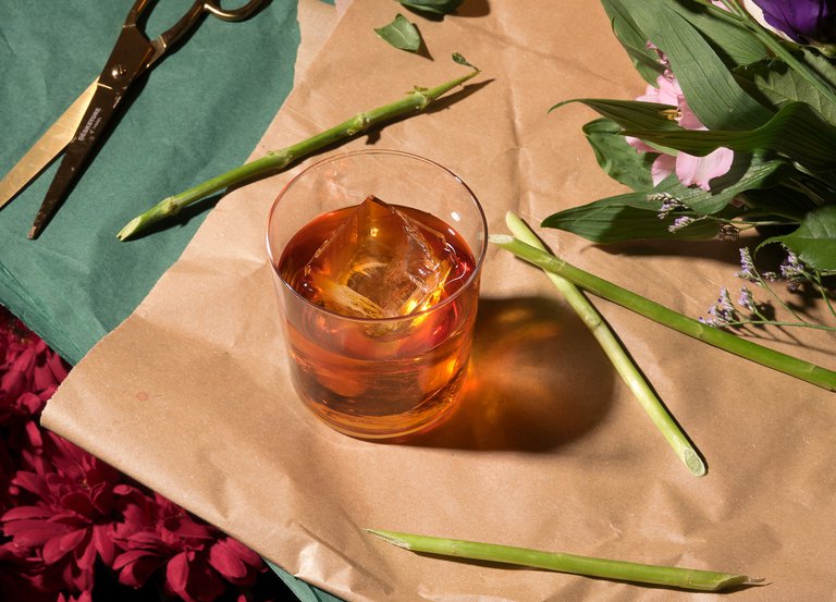 Bars in Stockholm. A drink at Lucy's Flowershop on Östermalm. Amber-colored liquid in a glass with ice.