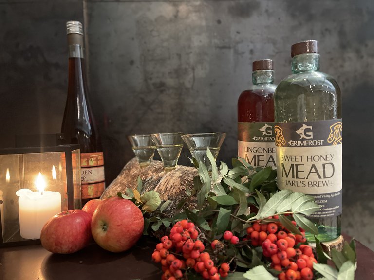 Candle, bottles, glasses, apples and berries.