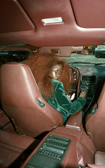 A woman sitting at the wheel of a large car.