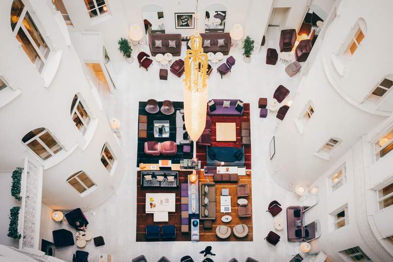 Design hotels in Stockholm. The bright lounge at Nobis hotel. Various chairs and soffas stand on a white floor, creating small seating groups for hotel guests to realx at.