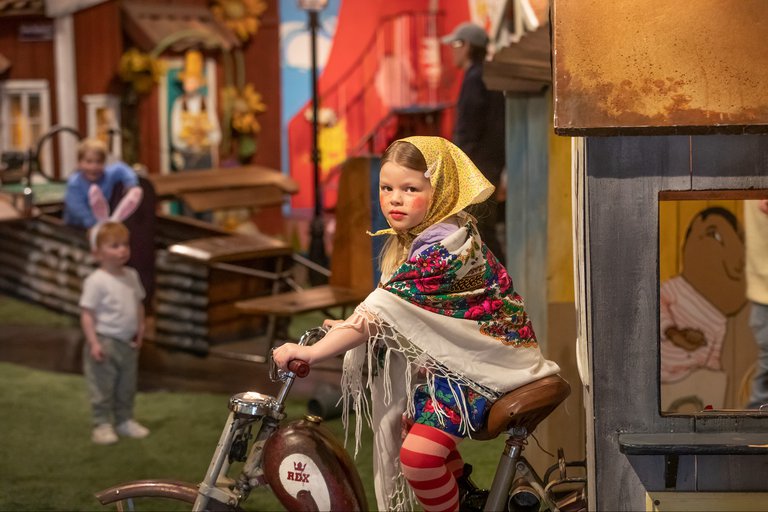 girl dressed up for Easter sitting on a bicycle