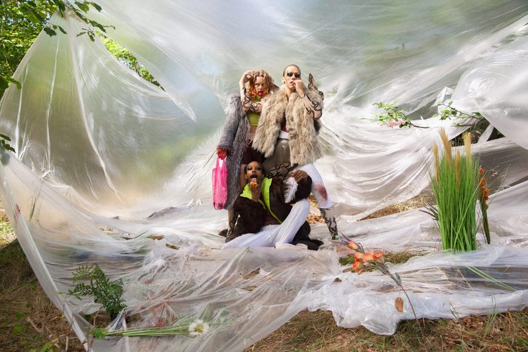 The dancers standing in the forest with the background covered with a transparent cloth.