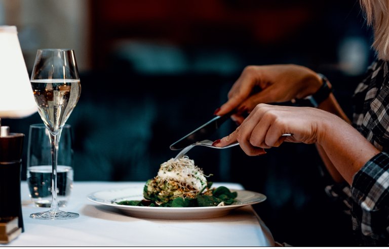 a person sitting at a table with a plate and two glasses on it
