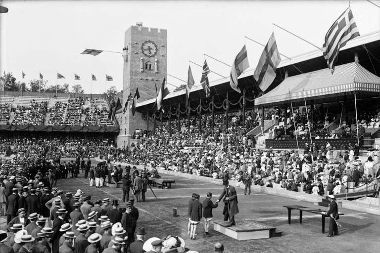 An photo of Stockholm Stadion taken in 1912 with many people on the field and in the seats.