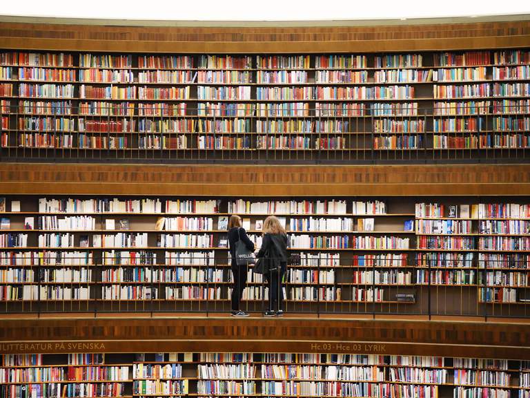 Culture in Stockholm. The Stockholm Public library. Two women stand in front of shelves packed with books.
