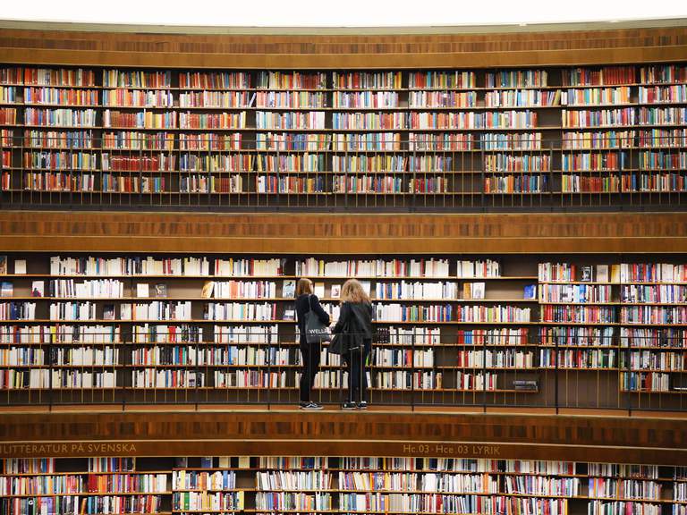 Culture in Stockholm. The Stockholm Public library. Two women stand in front of shelves packed with books.