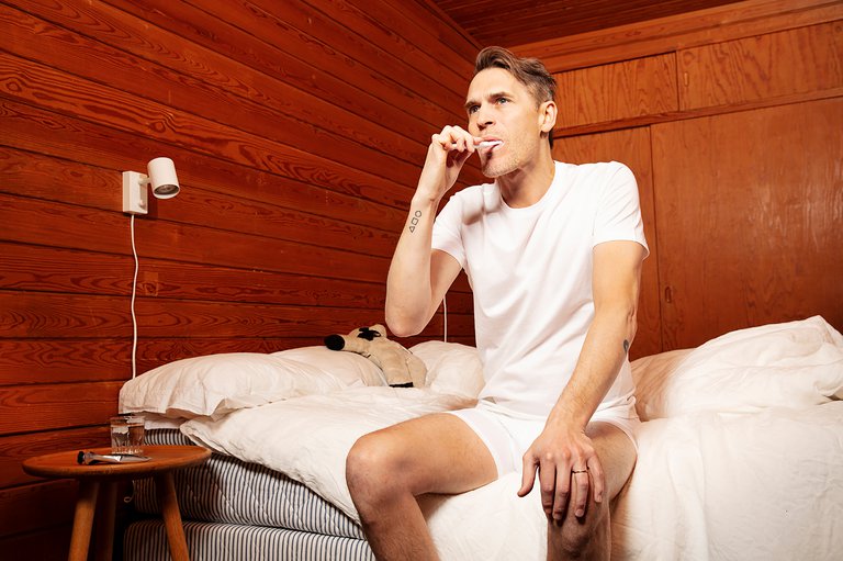 The musician Tingsek sitting on a bed.