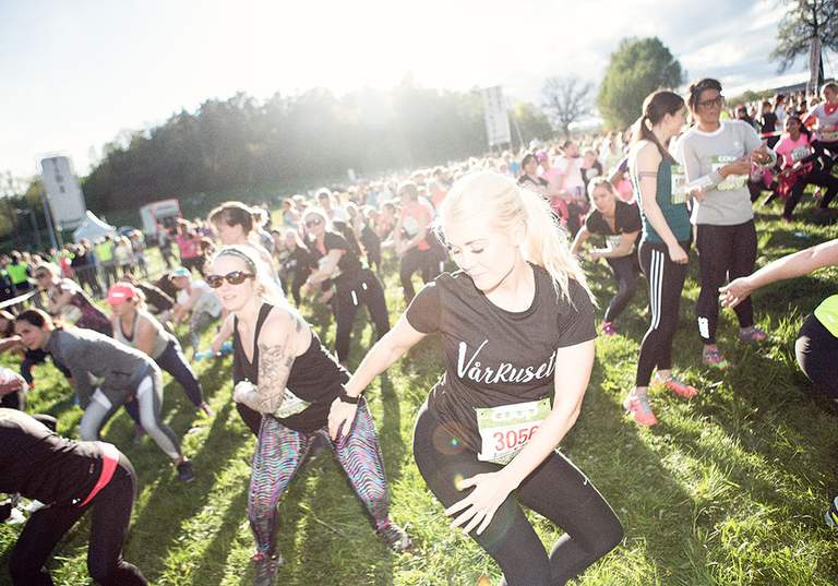 Women warming up before the race on a large green field.