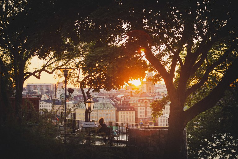A couple sit on a bench and watch the sun go down from Cornelisparken on Södermalm in Stockholm.