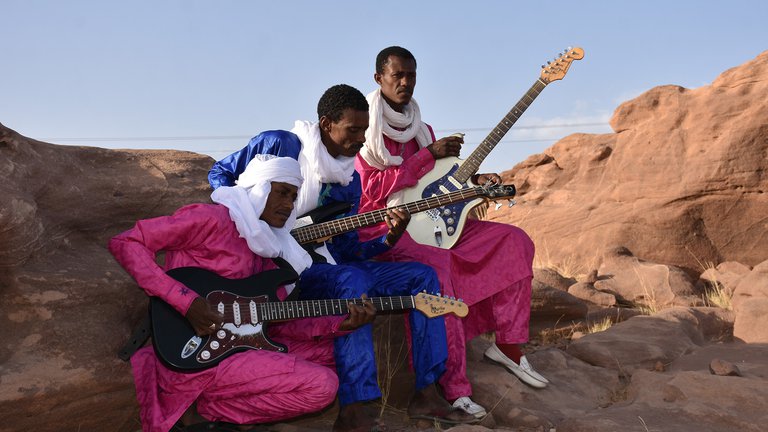 The musicians sitting with their guitars outside.