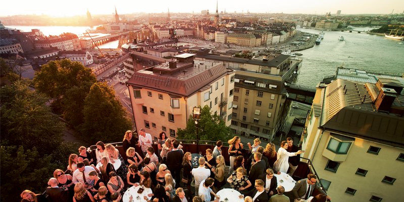 Summer evening in Stockholm. Champangebaren at Södra Teatern is full of people having drinks in the warm summer weather, with a view of Slussen and Old Town. The venerable Mossebacke Etablissement (which Södra Teatern) is one of Södermalm’s most popular