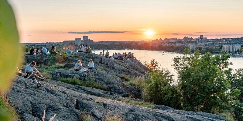 People sitting at Skinnarviksberget during sunset in the summer.