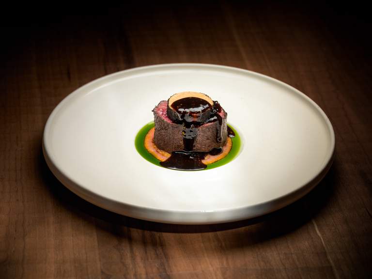 Restaurants in Stockholm. A plate of food at three-Michelin-starred Frantzén. A grilled piece of meat topped with gravy.