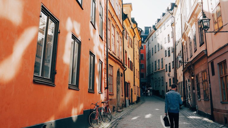 Spring in Gamla Stan. A young man walks down a narrow cobblestone street, line with old buildings.