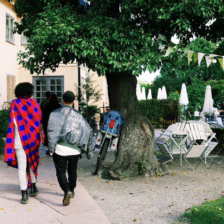 A couple wearing colorful trendy clothes seen from behind in a green area in summer or spring