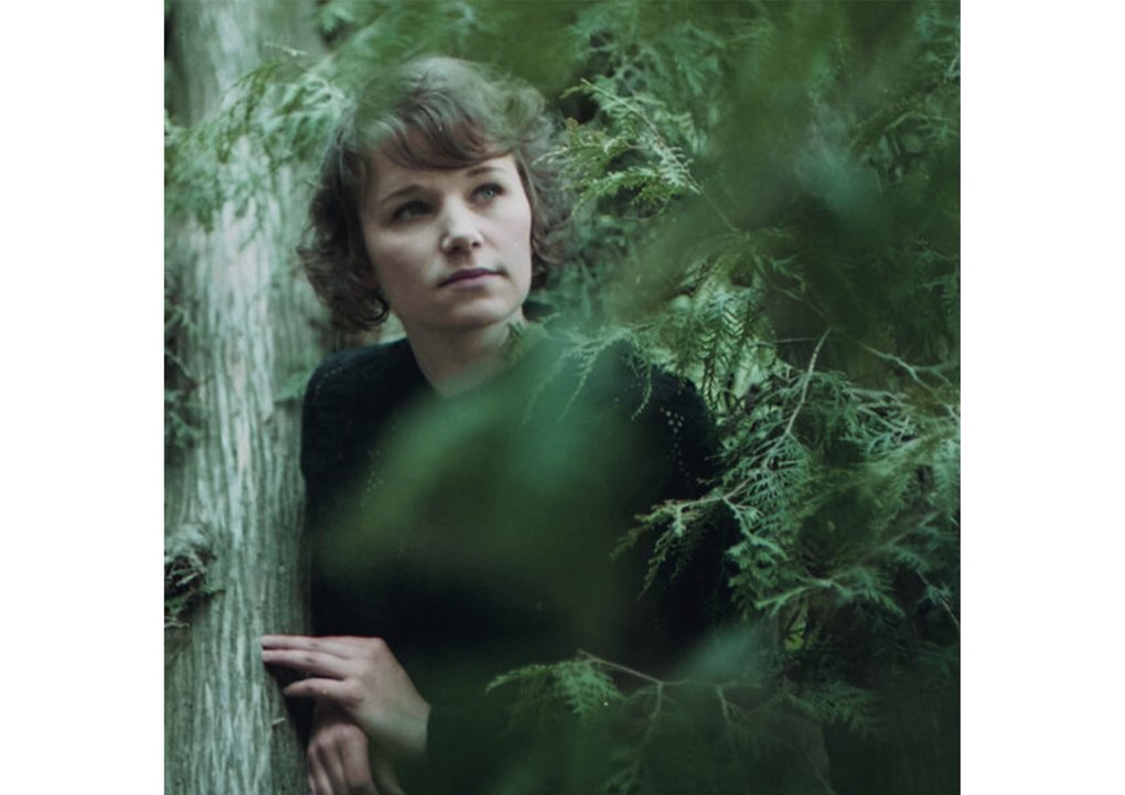 Iiris Viljanen standing in a forest landscape.