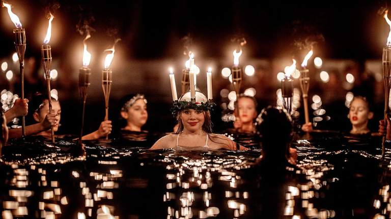 People with candles and torches in a swimming pool.
