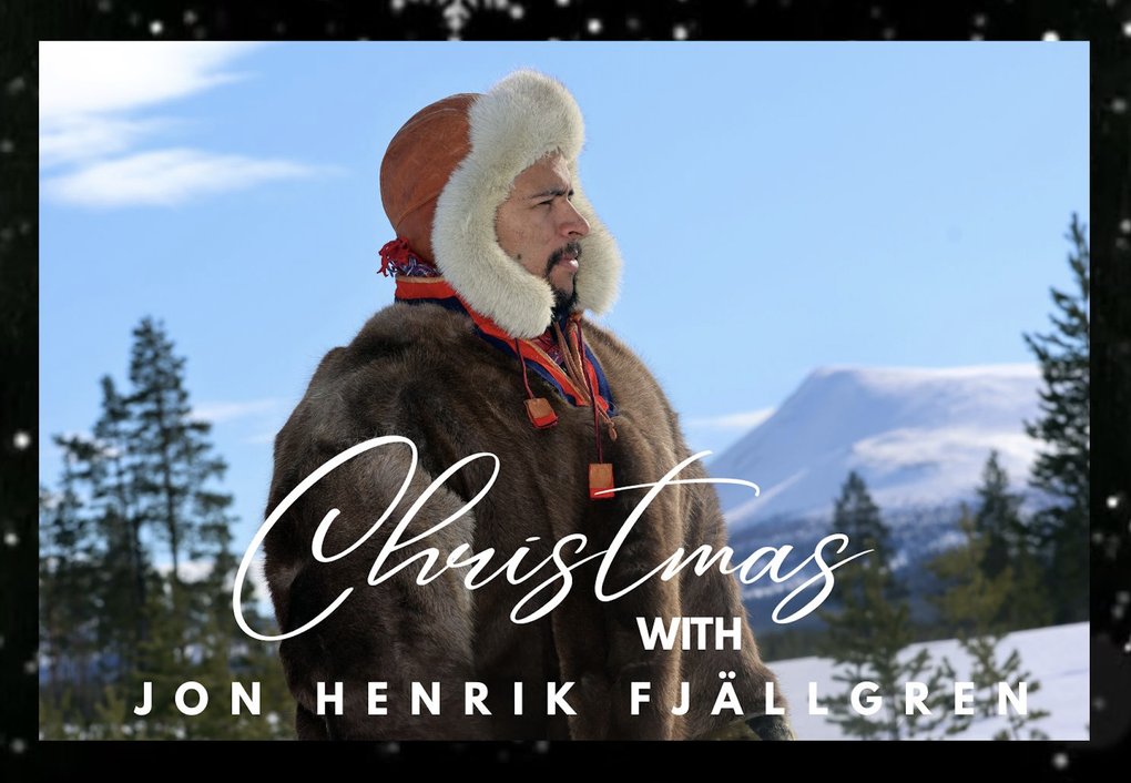 A man in fur clothing standing in profile in a snowy landscape with the words "Christmas with Jon Henrik Fjällgren" in the foreground..