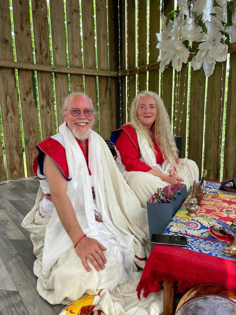 Two people in white and red clothes sitting on the floor at the table.