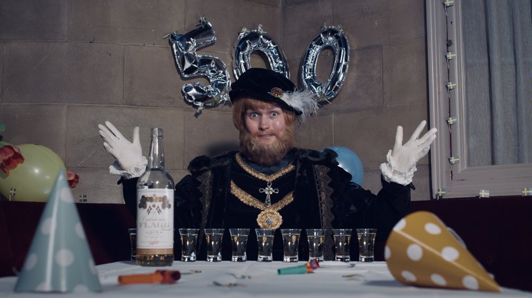 An actor in Gustav Vasa's costume is sitting at a table with a bottle and glasses.