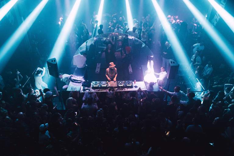 Nightclubs in Stockholm. A DJ is surrounded by a partying crowd at Krets.